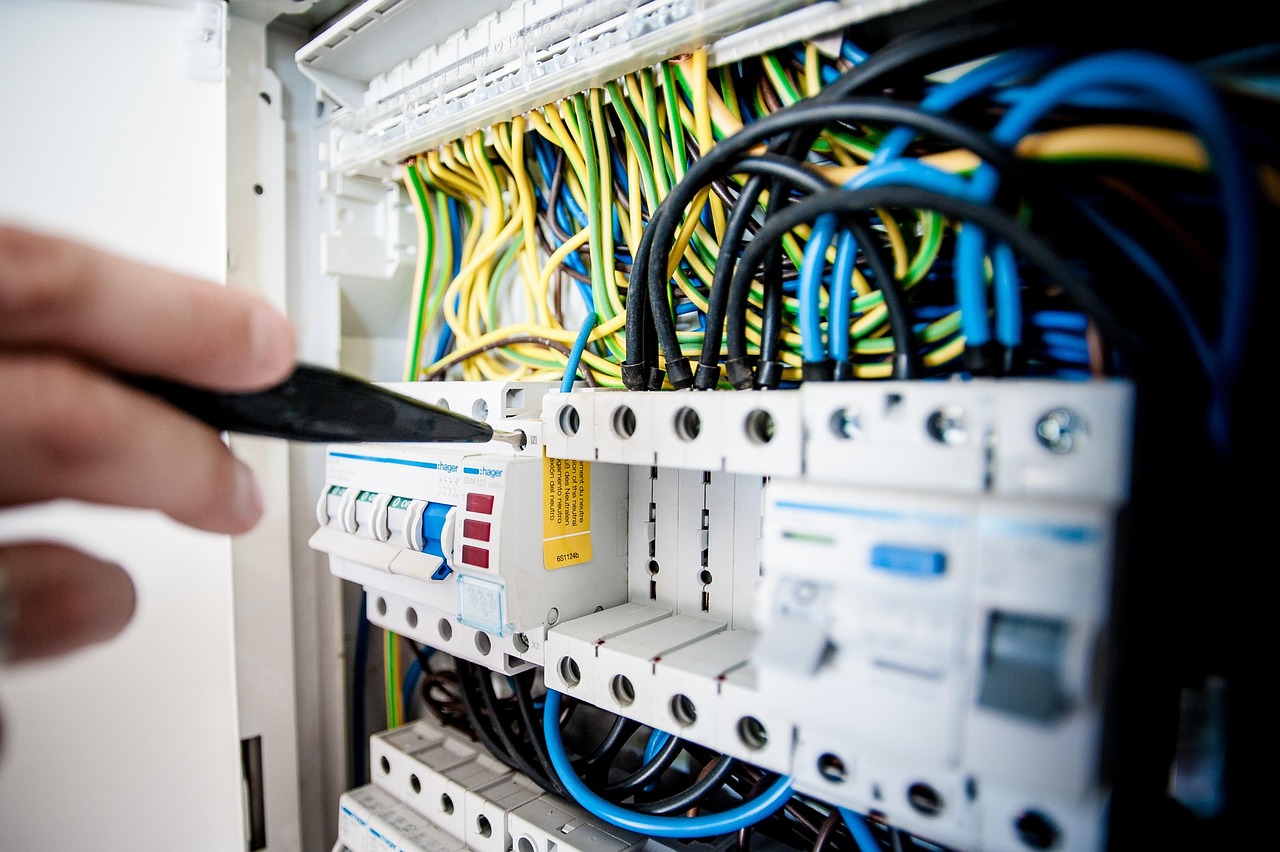 An electrician tightening terminals on an open consumer unit.